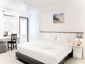 a white bedroom with a bed and a desk at Grand Sattahip Hotel in Sattahip +35 photos