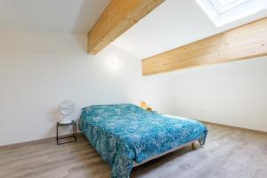 a bedroom with a bed with a blue comforter at Le gecko avec jacuzzi in Saint-Germain