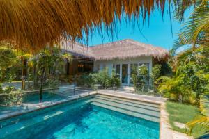 a villa with a swimming pool in front of a house at Hai Tide Beach Resort in Nusa Lembongan