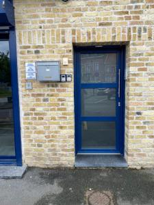 a blue door on a brick building with a window at Logement avec deux appartements sur deux étages in Wormhout