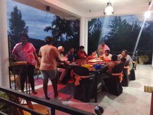 a group of people sitting around a table on a patio at Devil mountain villa- kalupahana in Etimole
