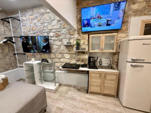 a kitchen with a refrigerator and a tv on a wall at TRAVELLERS CORFU TOWN Luxury Suites, Studios & Apartments in Ágios Rókkos