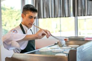 a man cooking pancakes on a stove in a kitchen at Diagoras Hotel All Inclusive in Faliraki