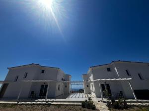 two white buildings with the sun in the sky at Meraki Nikiti in Nikiti