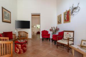 a living room with red chairs and a flat screen tv at Dimora Caiammari Luxury Hotel & Spa in Syracuse