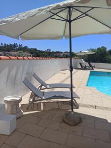 a pair of lounge chairs under an umbrella next to a swimming pool at Casa 56 in Sardoal