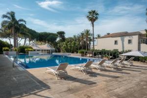 a row of lounge chairs and a swimming pool at Dimora Caiammari Luxury Hotel & Spa in Syracuse