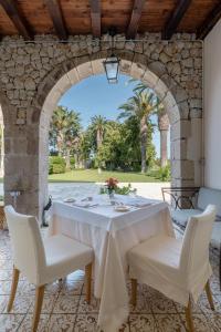 a table with white chairs and a stone archway at Dimora Caiammari Luxury Hotel & Spa in Syracuse