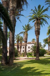 a row of palm trees in front of a building at Dimora Caiammari Luxury Hotel & Spa in Syracuse