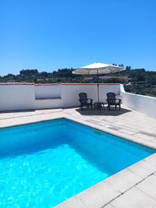 a swimming pool with two chairs and an umbrella at Casa 56 in Sardoal
