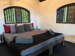 a large bed in a room with two windows at The Trogon Knuckles in Rangala