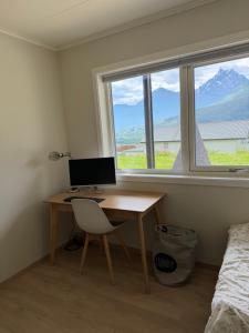 a desk with a computer in a room with a window at Mountain View apartment in Isfjorden