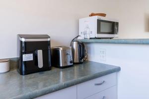 a kitchen counter with a coffee maker and a microwave at #2 Glenorchy Alpine Suite in Glenorchy