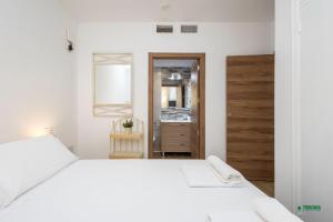 a white bedroom with a white bed and a mirror at Habitaciones Martín in San José