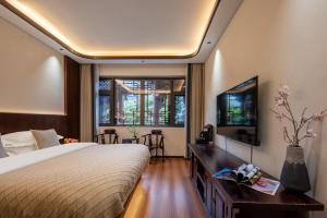 a bedroom with a bed and a flat screen tv at 木老爷客栈 in Lijiang