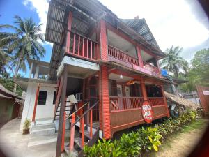 a red building with a porch and a balcony at Beachaus Resort in Pandan