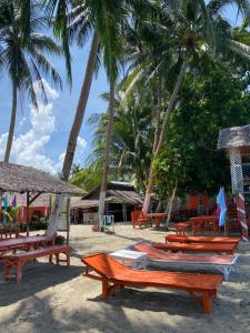 a group of benches on a beach with palm trees at Beachaus Resort in Pandan