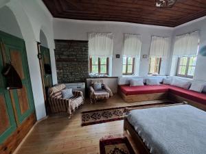 a bedroom with a bed and a couch and windows at Traditional GuestHouse Permet in Përmet