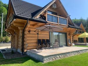 a log cabin with a patio and an umbrella at Bałtowska Osada in Bałtów