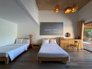 a bedroom with two beds and a desk and a tv at PUN Retreat in Quy Nhon