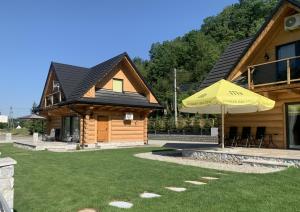 a log house with an umbrella and a lawn at Bałtowska Osada in Bałtów +52 photos