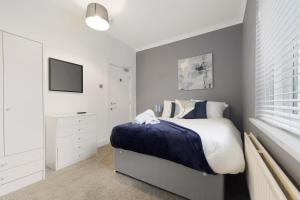 a white bedroom with a bed and a tv at 4BR Mitchell Street Apartment Sleeps 6 by Stay With Us in Shield Row