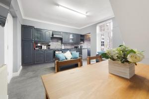 a living room with a table and a kitchen at 4BR Mitchell Street Apartment Sleeps 6 by Stay With Us in Shield Row