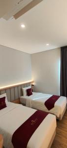 a hotel room with two beds in a room at AYMAN SYARIAH HOTEL in Surabaya
