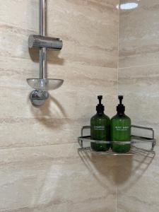 two green bottles on a shelf in a shower at Apartman Lambros in Soko Banja