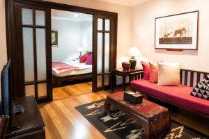 a living room with a red couch and a bed at The Siam Heritage Hotel in Bangkok +57 photos