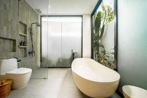 a bathroom with a tub and a toilet and a shower at Villa Scorpia 1 Bingin in Bingin Beach