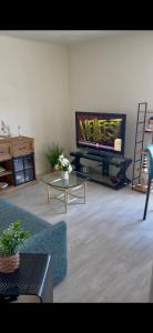 a living room with a tv and a couch and a table at Escale Berckoise Studio Cosy Proche des Phoques in Berck-sur-Mer