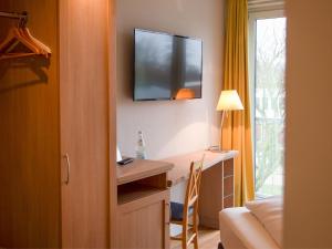 a hotel room with a desk and a television on the wall at BE BIO Hotel be natural - direkt am Wasser in Tönning