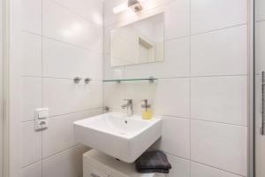 a white bathroom with a sink and a mirror at Ferienwohnung Talblick in Medebach +14 photos