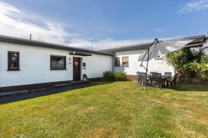 a house with a yard with chairs and an umbrella at Ferienwohnung Talblick in Medebach