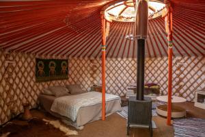 a bedroom with a bed in a yurt with a stove at Countryside yurt near Tõrva in Jõgeveste
