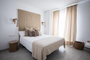 a bedroom with a white bed with a large window at Hostal Cervantes Playa in Garrucha