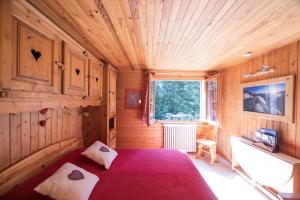 ein Schlafzimmer mit einem roten Bett in einem Holzzimmer in der Unterkunft La Datcharle in Pugny-Chatenod