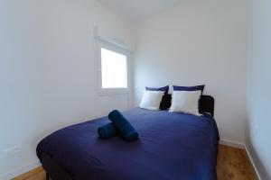 a bedroom with a blue bed with pillows and a window at T2 moderne Mon Toit in Mont-de-Marsan