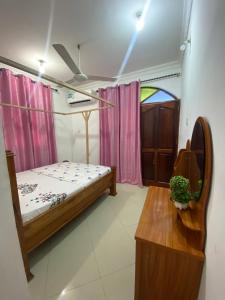 a bedroom with a bed and a table and a window at Hello Rafiki Stone town in Zanzibar City