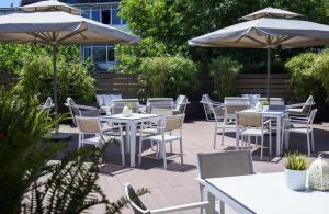 eine Terrasse mit weißen Tischen, Stühlen und Sonnenschirmen in der Unterkunft Anatolia Hotel in Thessaloniki