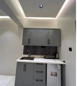 a kitchen with white cabinets and a refrigerator at شقق الأمل in Al ‘Awālī