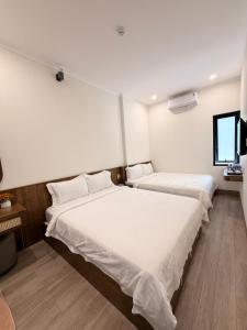 two beds in a room with white sheets at Hùng Anh Hotel in Phan Thiet