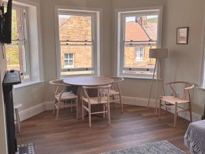 a dining room with a table and chairs and two windows at Holt Hall - First Floor Apartment in Matlock