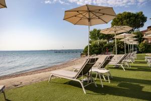 a row of chairs and umbrellas on the beach at Hotel Ocelle Thermae & Spa - Adults Only in Sirmione