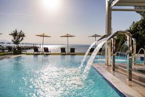 a swimming pool with a water slide in front of the ocean at Hotel Ocelle Thermae & Spa - Adults Only in Sirmione