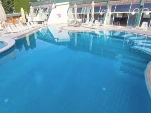 a swimming pool with blue water and white chairs at Apartment HORTENZIJA near Terme Topolšica in Topolšica