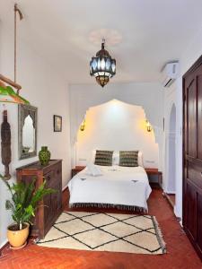 a bedroom with a white bed and a chandelier at Dar Yamina Andalusi in Chefchaouen