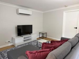 a living room with a couch and a flat screen tv at Units on Robertson in Mudgee
