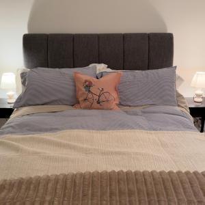 a bed with pillows and a bike on it at A beautiful stylish home in city centre in Camberley